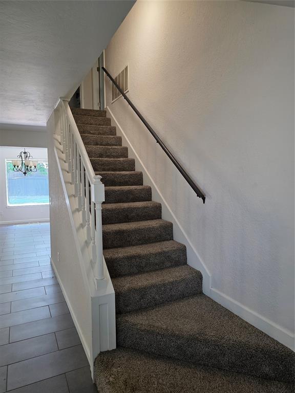 8813 Aaron Dr, Oklahoma City, OK 73132 - staircase featuring a chandelier and tile patterned floors