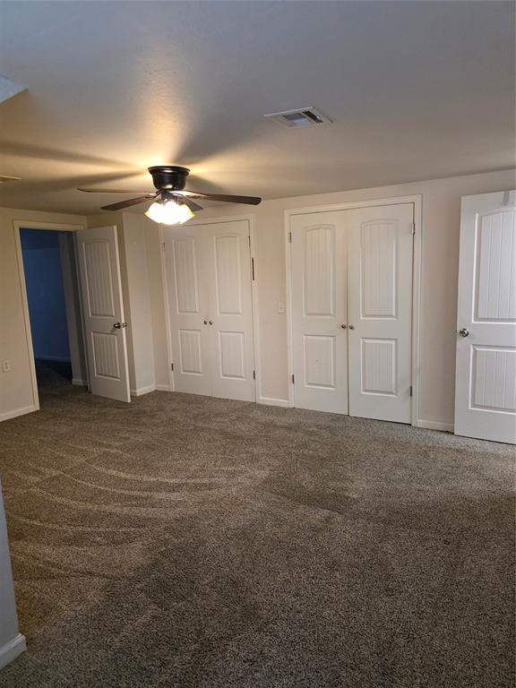 8813 Aaron Dr, Oklahoma City, OK 73132 - unfurnished bedroom featuring two closets, carpet flooring, and a ceiling fan