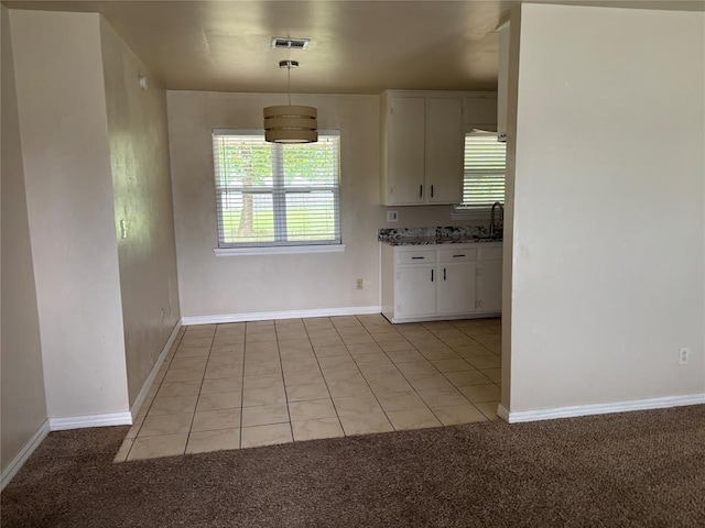 3305 N Mueller Ave, Bethany, OK 73008 - kitchen with white cabinets, healthy amount of natural light, light carpet, and light tile patterned floors