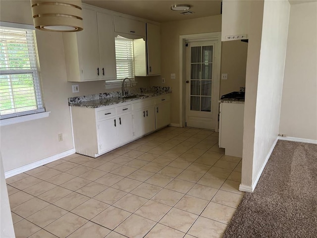 3305 N Mueller Ave, Bethany, OK 73008 - kitchen featuring white cabinets, plenty of natural light, light tile patterned flooring, and light stone counters
