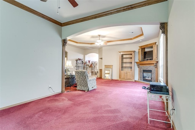 1308 River Birch Dr, Yukon, OK 73099 - living room featuring a ceiling fan, a fireplace, arched walkways, a raised ceiling, and ornamental molding