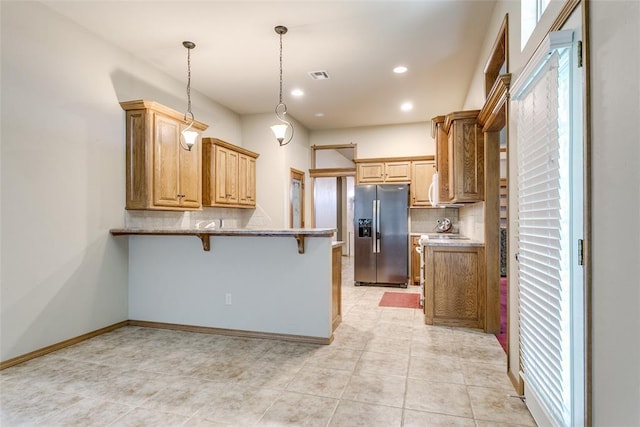 1308 River Birch Dr, Yukon, OK 73099 - kitchen featuring stainless steel fridge with ice dispenser, a peninsula, decorative backsplash, a breakfast bar area, and hanging light fixtures