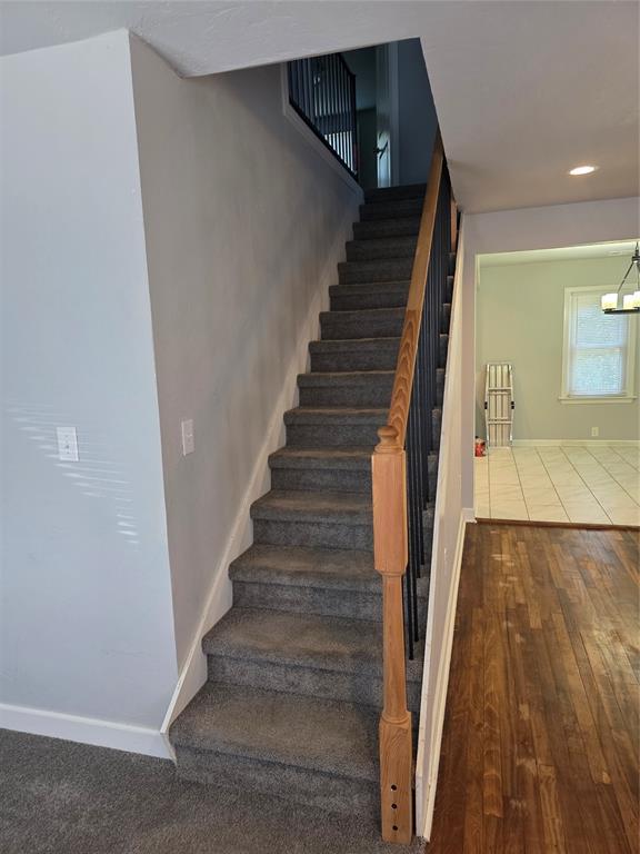 6101 NW 48th St, Warr Acres, OK 73122 - staircase with wood finished floors and a chandelier