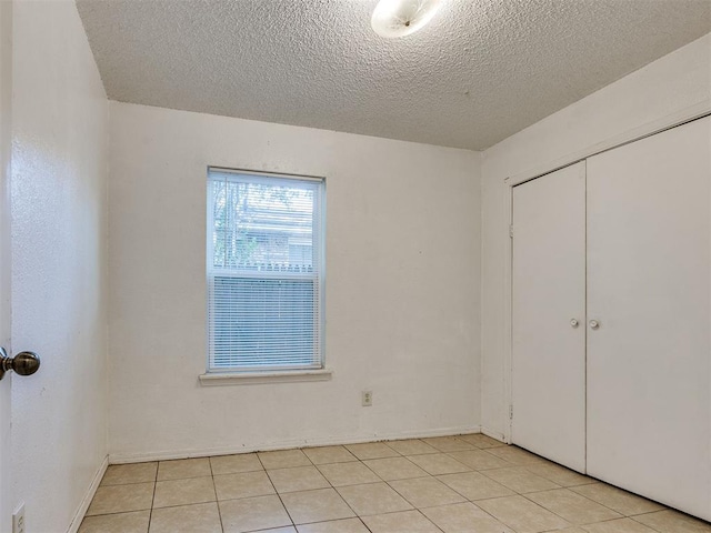 218 Windsor Way, Midwest City, OK 73110 - unfurnished bedroom featuring a textured ceiling, a closet, and light tile patterned floors