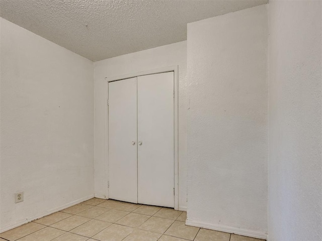 218 Windsor Way, Midwest City, OK 73110 - unfurnished bedroom featuring light tile patterned floors, a closet, and a textured ceiling