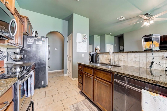 2500 SE 93rd St, Moore, OK 73160 - kitchen with stainless steel appliances, tasteful backsplash, dark stone counters, ceiling fan, and arched walkways