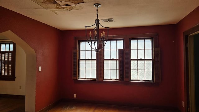 2609 NW 14th St, Oklahoma City, OK 73107 - unfurnished dining area with arched walkways, a chandelier, plenty of natural light, and wood finished floors