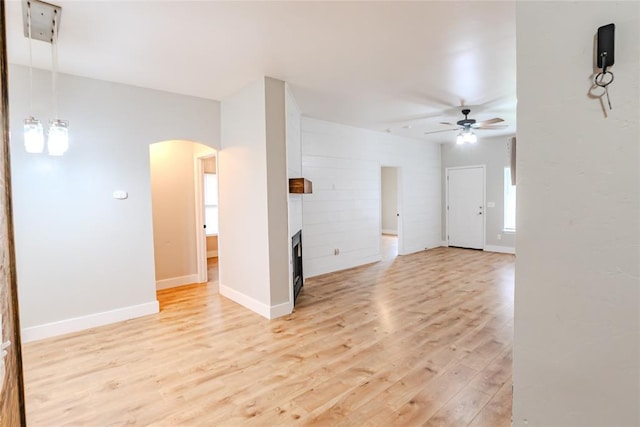 621 SW 7th St, Moore, OK 73160 - unfurnished room with a ceiling fan, light wood-type flooring, arched walkways, and a large fireplace