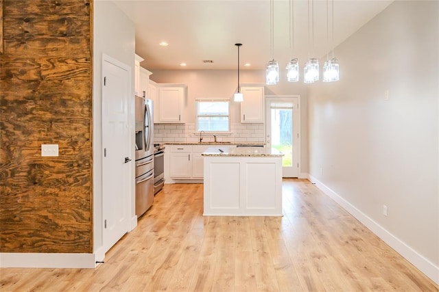 621 SW 7th St, Moore, OK 73160 - kitchen with tasteful backsplash, light wood-type flooring, white cabinetry, a kitchen island, and recessed lighting