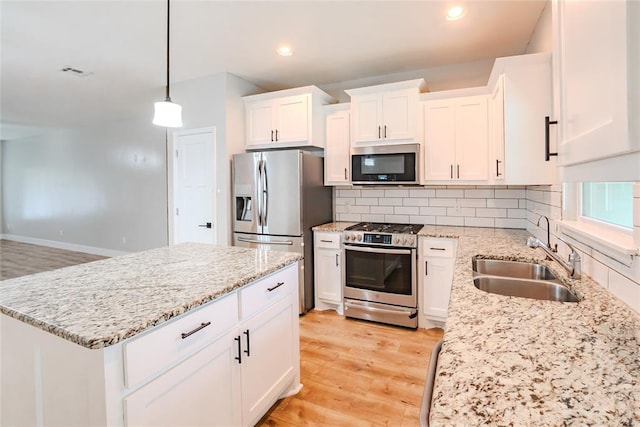 621 SW 7th St, Moore, OK 73160 - kitchen featuring appliances with stainless steel finishes, white cabinetry, tasteful backsplash, light wood-type flooring, and light stone counters