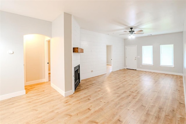 621 SW 7th St, Moore, OK 73160 - unfurnished living room featuring a ceiling fan, light wood-type flooring, a fireplace, and arched walkways