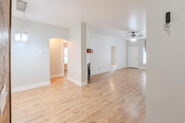 621 SW 7th St, Moore, OK 73160 - unfurnished living room featuring a ceiling fan, arched walkways, light wood-style floors, and a fireplace