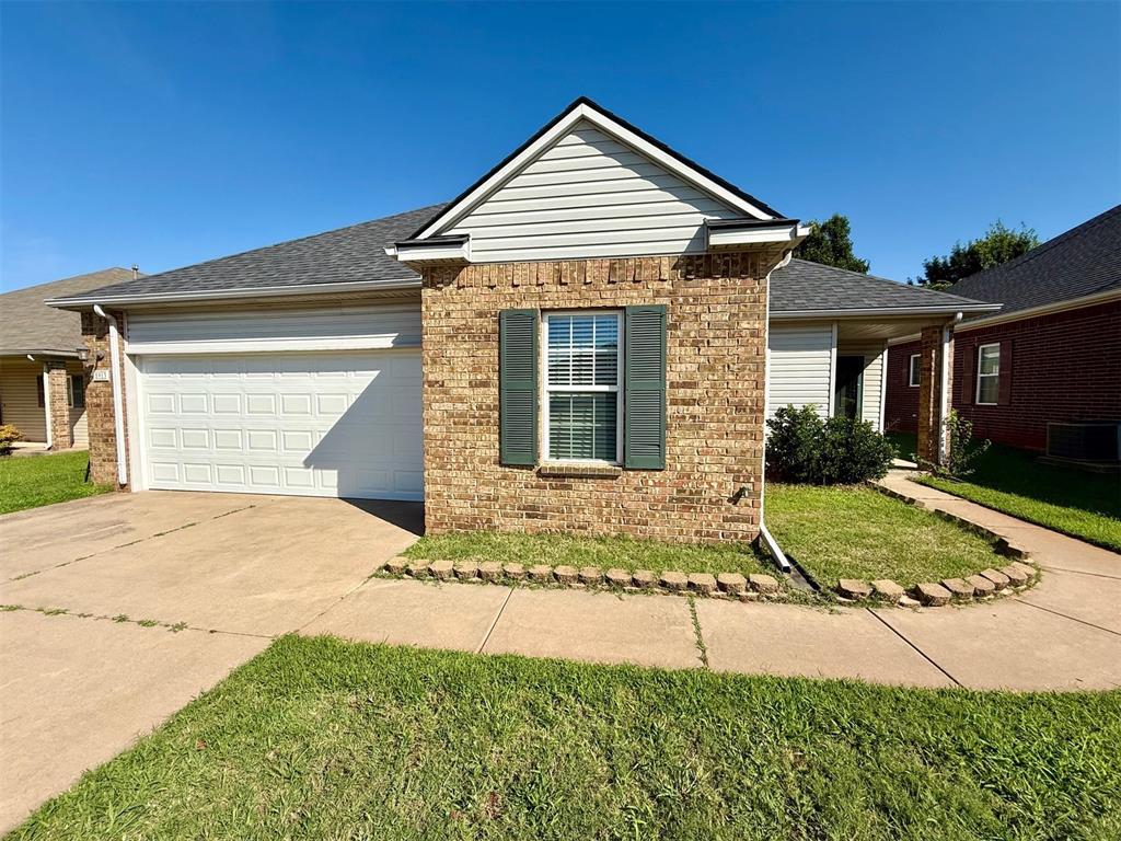5913 SE 67th St, Oklahoma City, OK 73135 - ranch-style house featuring driveway, brick siding, an attached garage, a front lawn, and roof with shingles