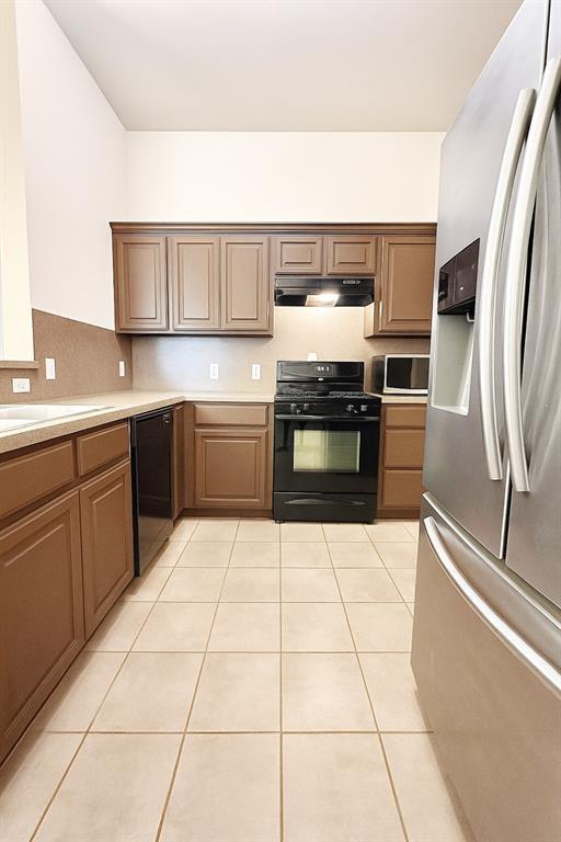 9524 SW 26th St, Oklahoma City, OK 73128 - kitchen featuring black appliances, under cabinet range hood, light countertops, and light tile patterned flooring
