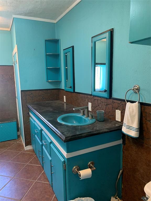 123 N Payne St, Fort Cobb, OK 73038 - bathroom featuring tile walls, vanity, crown molding, tile patterned flooring, and a textured ceiling