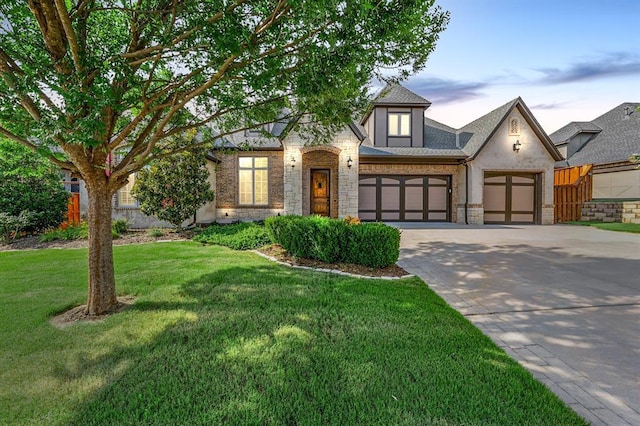 2725 Open Range Rd, Edmond, OK 73034 - view of front of home featuring driveway, a garage, a front yard, stone siding, and stucco siding