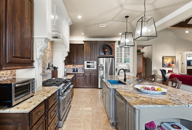 2725 Open Range Rd, Edmond, OK 73034 - kitchen with stainless steel appliances, stone tile floors, decorative backsplash, a large island with sink, and hanging light fixtures