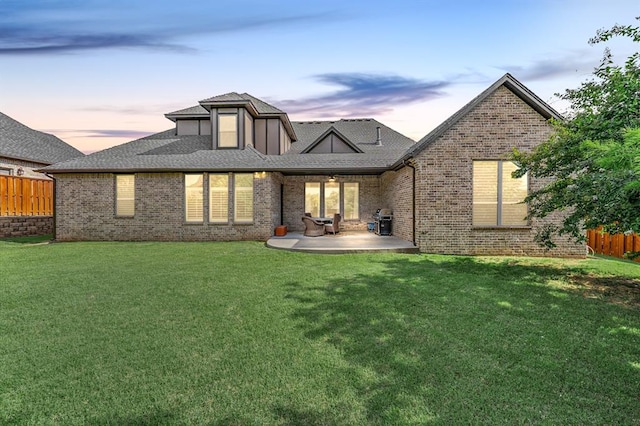 2725 Open Range Rd, Edmond, OK 73034 - back of property at dusk with a patio, brick siding, and a shingled roof