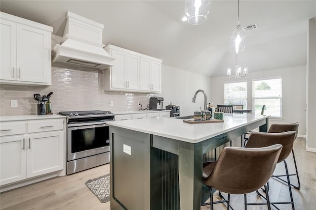 6605 NW 150th Ter, Oklahoma City, OK 73142 - kitchen with gas stove, custom range hood, vaulted ceiling, backsplash, and a kitchen island with sink