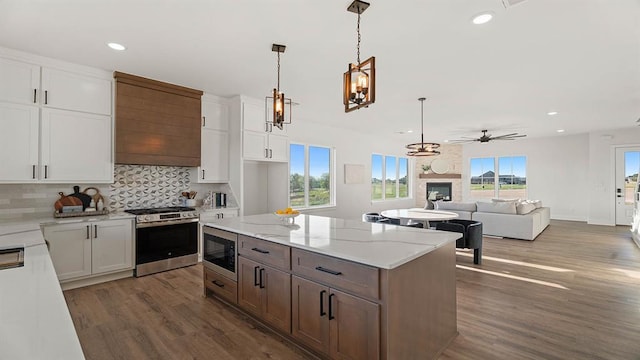 4676 Ranchero Dr, Edmond, OK 73025 - kitchen featuring stainless steel appliances, a fireplace, wood finished floors, white cabinetry, and recessed lighting