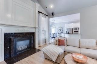17009 Wales Green Ave, Edmond, OK 73012 - living area featuring vaulted ceiling, light wood-type flooring, and a fireplace with flush hearth