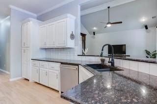17009 Wales Green Ave, Edmond, OK 73012 - kitchen with stainless steel dishwasher, a ceiling fan, white cabinets, dark stone countertops, and tasteful backsplash