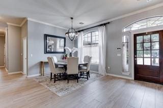 17009 Wales Green Ave, Edmond, OK 73012 - dining room with wood finished floors, a chandelier, and ornamental molding
