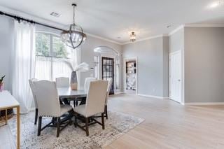 17009 Wales Green Ave, Edmond, OK 73012 - dining room featuring wood finished floors, arched walkways, ornamental molding, and a chandelier