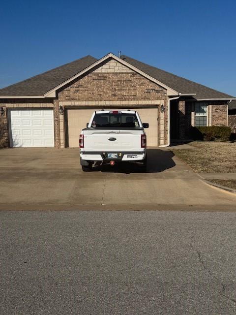 8017 NW 159th St, Edmond, OK 73013 - ranch-style home with an attached garage, concrete driveway, brick siding, and roof with shingles