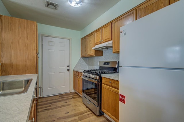 2013 Creekridge Dr, Oklahoma City, OK 73141 - kitchen featuring freestanding refrigerator, gas range, under cabinet range hood, light wood finished floors, and light countertops