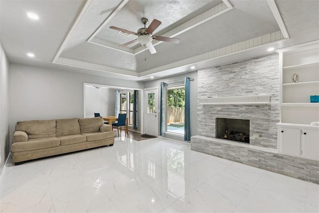 10412 NW 37th St, Yukon, OK 73099 - living room with marble finish floors, ceiling fan, a tray ceiling, and a fireplace