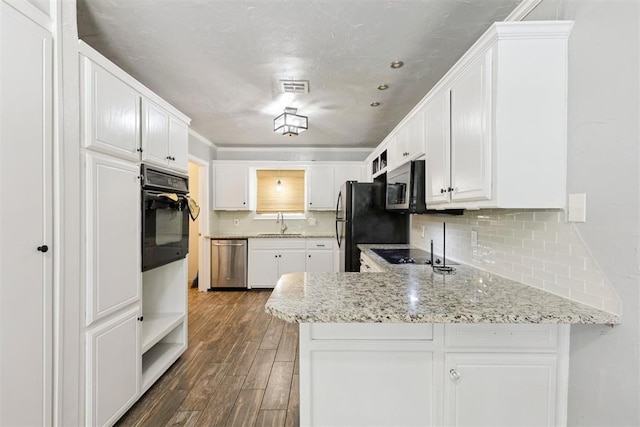 10412 NW 37th St, Yukon, OK 73099 - kitchen with a peninsula, black appliances, decorative backsplash, and dark wood-type flooring