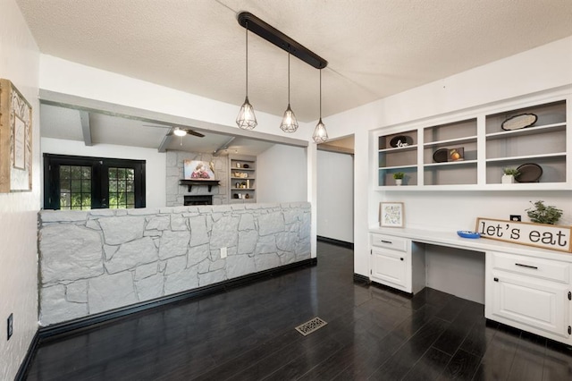 10520 Ricky Ln, Midwest City, OK 73130 - kitchen with built in study area, white cabinets, a stone fireplace, open shelves, and dark wood-style flooring
