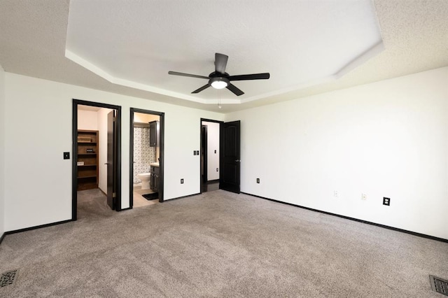 10520 Ricky Ln, Midwest City, OK 73130 - unfurnished bedroom with a tray ceiling, carpet floors, ensuite bathroom, and ceiling fan