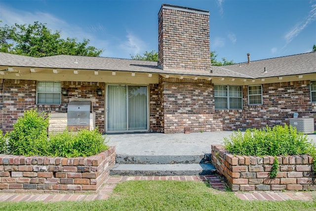 2532 Lancaster Ln, Oklahoma City, OK 73116 - doorway to property featuring a chimney, brick siding, a patio, and a shingled roof