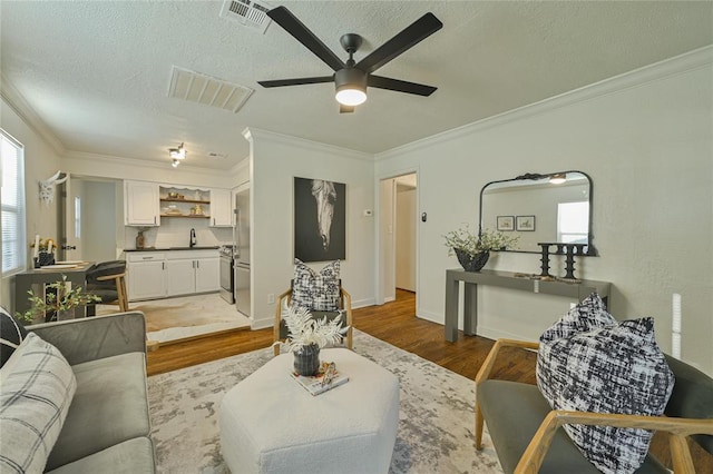 6109 NW 55th St, Oklahoma City, OK 73122 - living area featuring ornamental molding, wood finished floors, a textured ceiling, and ceiling fan