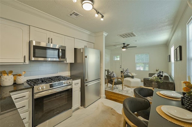 6109 NW 55th St, Oklahoma City, OK 73122 - kitchen with appliances with stainless steel finishes, ornamental molding, a textured ceiling, white cabinetry, and tasteful backsplash