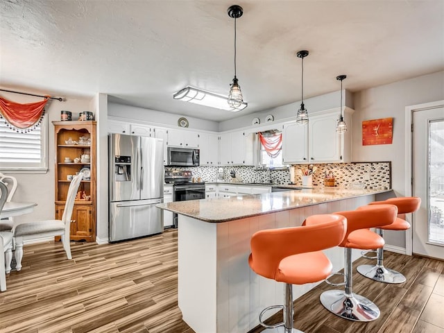 617 Hoehner Ave, Okarche, OK 73762 - kitchen with appliances with stainless steel finishes, a peninsula, light wood-style floors, and healthy amount of natural light