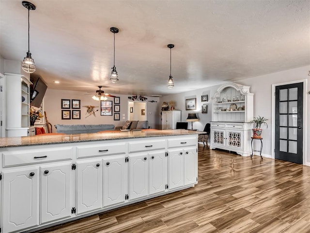 617 Hoehner Ave, Okarche, OK 73762 - kitchen with open floor plan, a ceiling fan, white cabinets, light wood-style flooring, and pendant lighting