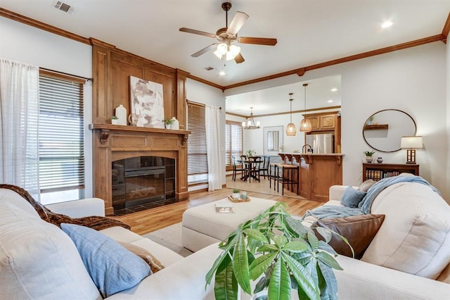 825 Silver Tree Dr, Choctaw, OK 73020 - living area featuring ornamental molding, light wood-style floors, ceiling fan, a fireplace with flush hearth, and a chandelier