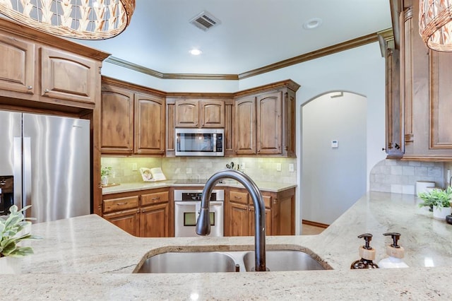 825 Silver Tree Dr, Choctaw, OK 73020 - kitchen featuring stainless steel appliances, light stone counters, arched walkways, crown molding, and decorative backsplash
