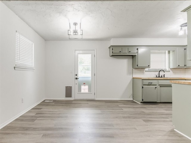 2550 Clarke St, Choctaw, OK 73020 - kitchen featuring light countertops, light wood-style floors, a textured ceiling, backsplash, and gray cabinets