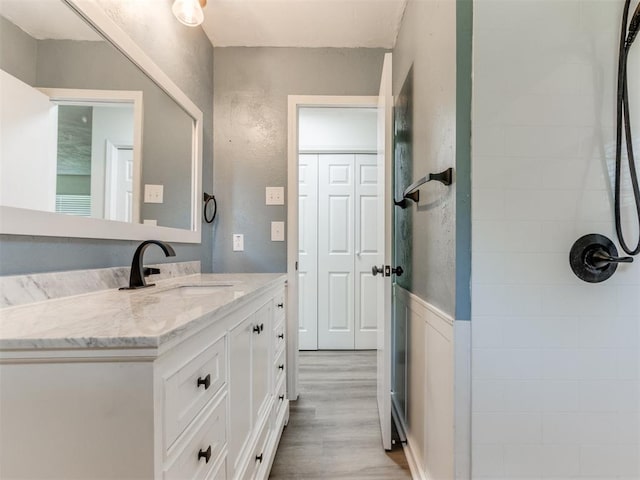 2550 Clarke St, Choctaw, OK 73020 - full bathroom featuring vanity, wood finished floors, a tile shower, and a textured wall