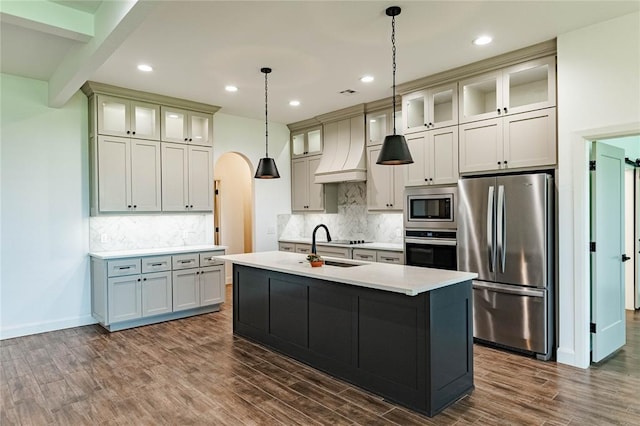 14704 Ashore Dr, Oklahoma City, OK 73142 - kitchen with appliances with stainless steel finishes, custom exhaust hood, a kitchen island with sink, dark wood-style flooring, and recessed lighting
