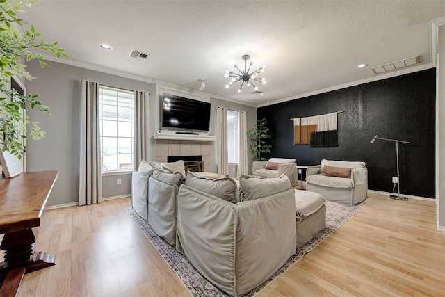 4155 NW Terrace Hills Rd, Piedmont, OK 73078 - living room with light wood-type flooring, ornamental molding, a chandelier, a fireplace, and recessed lighting