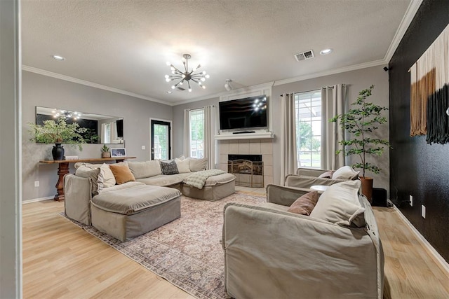 4155 NW Terrace Hills Rd, Piedmont, OK 73078 - living room with wood finished floors, plenty of natural light, a chandelier, crown molding, and a tiled fireplace