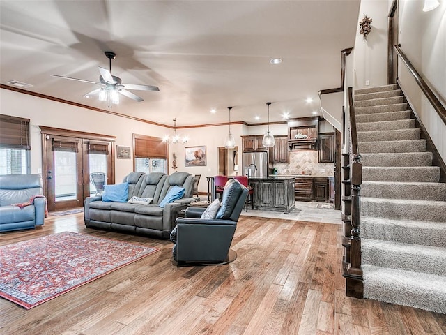 17401 Melville Ln, Edmond, OK 73012 - living room featuring a ceiling fan, light wood-type flooring, stairs, a chandelier, and crown molding