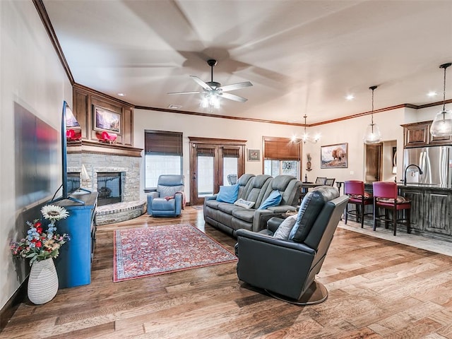 17401 Melville Ln, Edmond, OK 73012 - living area with crown molding, ceiling fan, light wood-style floors, a stone fireplace, and a chandelier