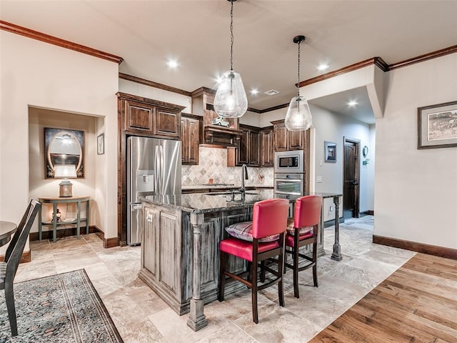17401 Melville Ln, Edmond, OK 73012 - kitchen featuring appliances with stainless steel finishes, dark stone countertops, crown molding, decorative backsplash, and a kitchen island with sink