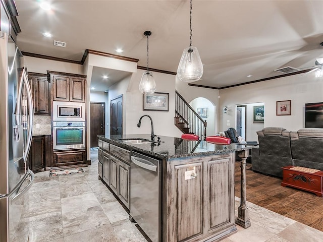 17401 Melville Ln, Edmond, OK 73012 - kitchen with stainless steel appliances, ornamental molding, dark stone counters, a breakfast bar, and an island with sink